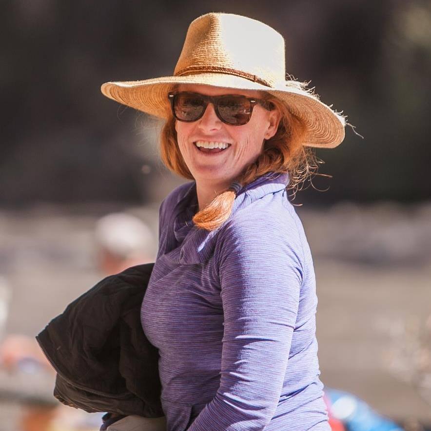 Brooke Johnson, Tumbleweed Travel Co's founder, wears a straw hat and sunglasses and smiles joyfully at the camera