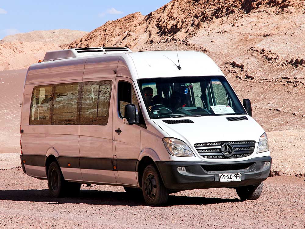 class-c-sprinter-van A white Class C Sprinter Van parked in front of a red desert hill