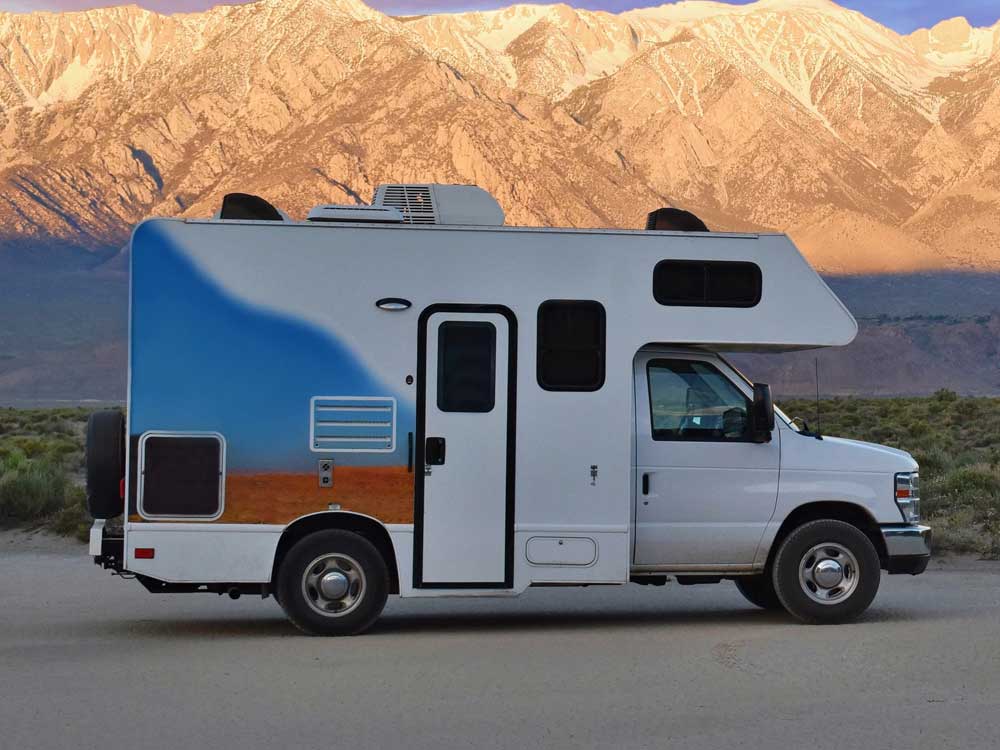 small-class-c-rv A small Class C rental RV parked in front of snow-capped mountains at dusk