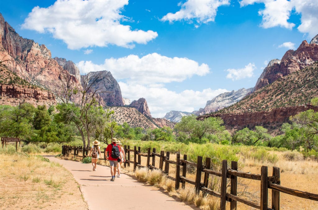 People hiking in the mountains. Family walking on pathway. Backpackers on summer trip. Beautiful red mountain landscape Zion National Park, Utah, USA People hiking in the mountains. Family walking on pathway. Backpackers on summer trip. Beautiful red mountain landscape Zion National Park Utah USA from Tumbleweed Travel