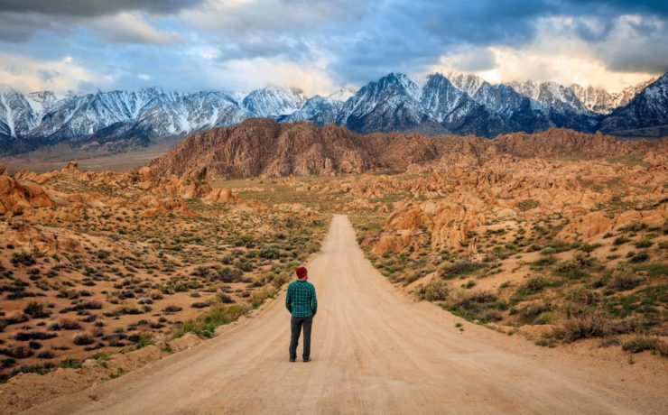 Value Experiences Over Things Man standing on a dirt road in the Sierra Nevada Mountains California USA. scaled from Tumbleweed Travel