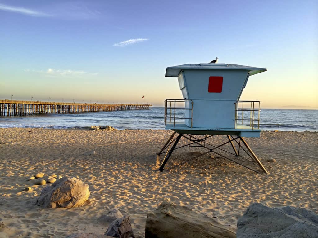 Lifeguard booth towering above sand near historic wooden pier San Buenaventura Southern California from Tumbleweed Travel