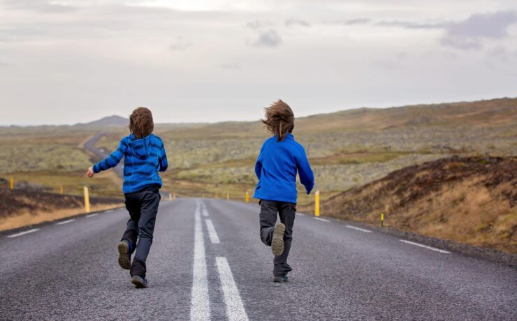 How to Make Road Trips Fun for Kids Kids running on an empty road in beautiful nature in Snaefellsjokull National Park in Iceland autumntime on sunset scaled from Tumbleweed Travel